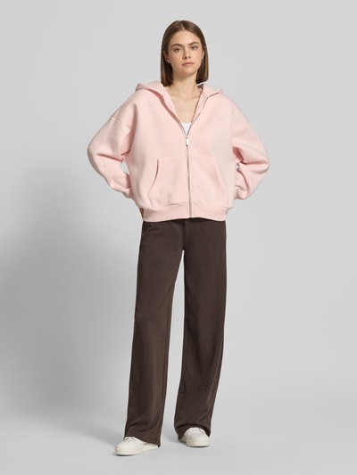 Frauenmodel trägt Straight Fit Sweatpants mit Tunnelzug von REVIEW, mieszanka bawełny, krój straight fit, elastyczny pas, tunel, długość wewnętrzna nogawki w rozmiarze S: 85 cm, ciemnobrązowe, gładka tekstura, prosty fason, Ganzkörperansicht von vorne.