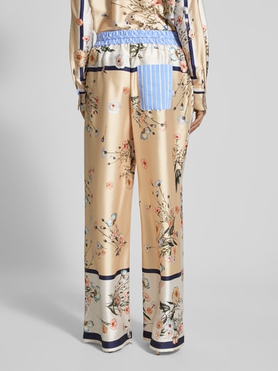 Frauenmodel trägt Wide Fit Stoffhose aus Satin von Liu Jo White mit floraler Allover-Print, elastischer Bund mit Tunnelzug, Ganzkörperansicht Rückansicht.