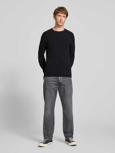 Männermodel trägt Slim Fit Pullover aus reiner Baumwolle von REVIEW in Schwarz, kombinierbar, Strick-Optik, Rundhals, Ganzkörperansicht von vorne.