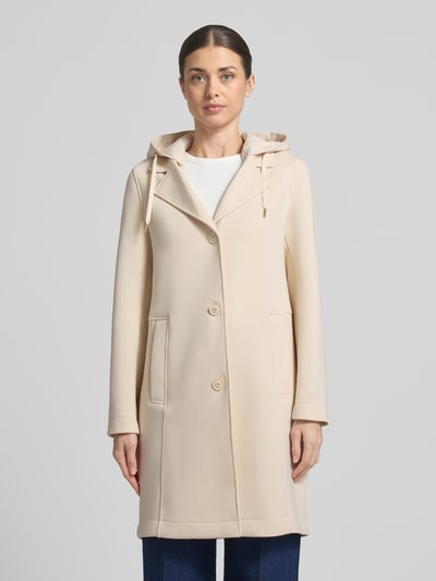Frauenmodel trägt Regular Fit Kurzmantel mit Kapuze von s.Oliver RED LABEL in Beige mit langen Ärmeln und Leistentaschen, Ganzkörperansicht von vorne.