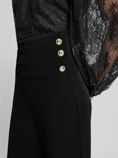 Frauenmodel trägt Flared Cut Hose mit Knöpfen von Rinascimento, schwarzer Material-Mix mit Stretch, Nahaufnahme Oberkörper