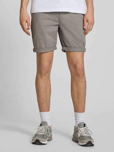 Męski model nosi Regular Fit Shorts mit Münztasche od Superdry, bawełniana mieszanka, detaliczny widok z przodu, Szerokość w rozmiarze 32: 44 cm, długość nogawki od wewnątrz: 20 cm, boczna kieszonka, tylne kieszenie, zapięcie na guzik i zamek.