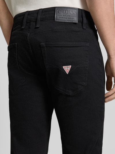 Männermodel trägt Slim Fit Jeans im 5-Pocket-Design Modell 'ANGELS' von Guess aus Baumwoll-Elasthan-Mix, Detailaufnahme Rückansicht.