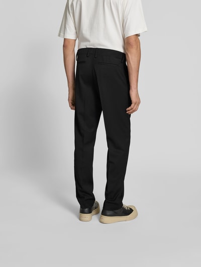 Männermodel trägt Slim Fit Anzughose mit Woll-Anteil von Filippa K, Elastischer-Material-Mix, Bundfalten, schwarz, Ganzkörperansicht Rückansicht.