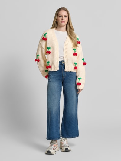 Frauenmodel trägt Oversized Strickjacke mit Zier-Applikationen von Apricot, Grobstrick, offene Vorderseite, Ganzkörperansicht von vorne.