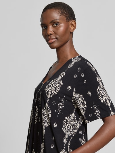 Frauenmodel trägt knielanges Kleid mit V-Ausschnitt Modell 'Floy' von FREE/QUENT, schwarz mit weißem Muster, Material-Mix mit Stretch-Anteil, Nahaufnahme Oberkörper.