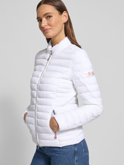 Frauenmodel trägt Steppjacke mit Zweiwege-Reißverschluss Modell 'JUDY' von Frieda & Freddies, weiß, Slim Fit, Stehkragen, Ganzkörperansicht von vorne, Rückenlänge 57 cm, Schulterbreite 40 cm, Brustweite 48 cm, Ärmellänge 64 cm, Reißverschlusstaschen, glatte Textur.
