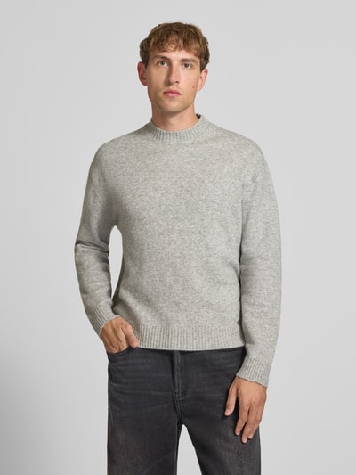 Männermodel trägt Relaxed Fit Strickpullover aus Material-Mix mit Baumwoll-Anteil von REVIEW in Hellgrau, elastische Abschlüsse, Nahaufnahme Oberkörper.