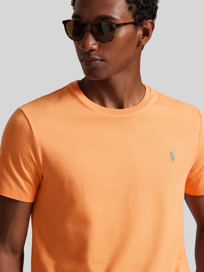 Männermodel trägt Regular Fit T-Shirt aus reiner Baumwolle von Polo Ralph Lauren in Orange, unifarben, Logo-Stitching, Nahaufnahme Oberkörper.