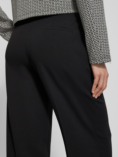 Frauenmodel trägt Stoffhose mit weitem Bein und Bügelfalten von Betty Barclay, Material-Mix mit Stretch-Anteil, Paspeltaschen am Gesäß, Detailaufnahme Rückansicht.