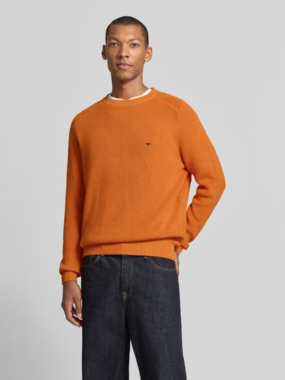 Männermodel trägt Regular Fit Strickpullover aus reiner Baumwolle von Fynch-Hatton in Orange, elastische Abschlüsse, Label-Detail, Ganzkörperansicht von vorne