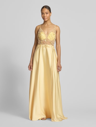 Modelka kobieca ma na sobie 'Abendkleid mit floralem Ziersteinbesatz' od Laona, żółty satynowy materiał, zwężany krój, kwiatowy zdobiony kamieniami i cekinami, cienkie ramiączka, dekolt w kształcie litery V, półprzezroczyste wstawki, rozcięcie z przodu, długość tyłu w rozmiarze 36: 124 cm, szerokość w rozmiarze 36: 30 cm, widok całej sylwetki z przodu.