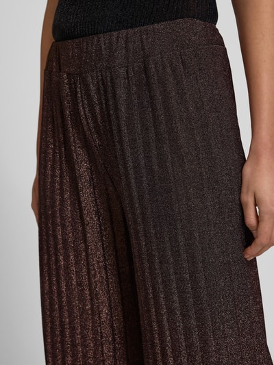 Frauenmodel trägt Stoffhose mit elastischem Bund von ZABAIONE in dunklem Braun, locker geschnitten, feine schimmernde Struktur, Nahaufnahme Oberkörper.