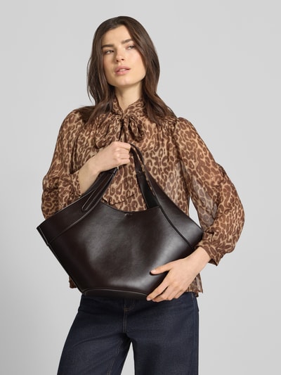 Frauenmodel trägt Handtasche mit verstellbaren Tragehenkeln von Mango in dunklem Braun, Hauptfach mit Hakenverschluss, Ganzkörperansicht von vorne.