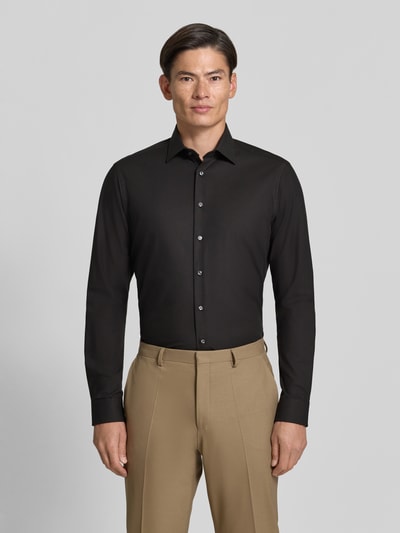 Männermodel trägt Regular Fit Business-Hemd mit Kentkragen von Christian Berg Men in Schwarz, glatte Textur, Ganzkörperansicht von vorne. Baumwoll-Mix mit Stretch-Anteil, abgerundeter Saum, Rückenlänge 80 cm, Schulterbreite 48 cm, Ärmellänge 65 cm.