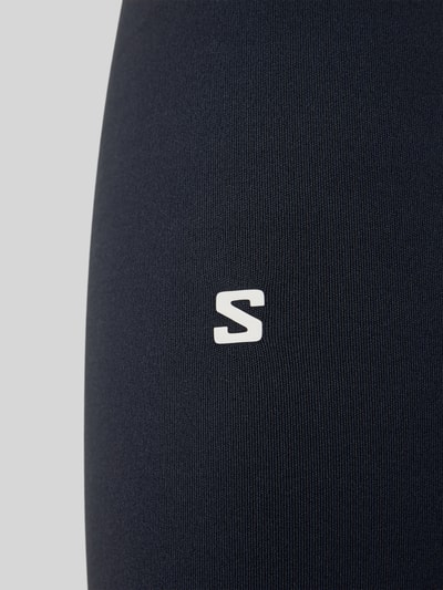 Produktfoto, Leggings mit Stretch-Anteil Modell 'SHKOUT' von Salomon, Elastischer-Material-Mix, Label-Print, dunkle Farbe, glatte Textur.