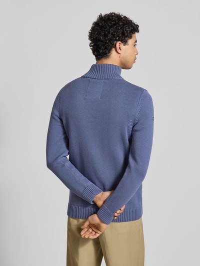 Männermodel trägt Slim Fit Pullover in Strick-Optik von Superdry in Blau mit Stehkragen, Logo-Stitching, Rückenlänge 70 cm, Ärmellänge 65 cm, Ganzkörperansicht Rückansicht.