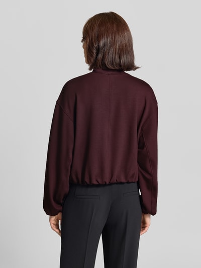 Frauenmodel trägt Regular Fit Sweatjacke aus Viskose-Mix von Brax in Dunkelrot, kombiniert mit schwarzer Hose, Ganzkörperansicht Rückansicht.