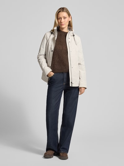 Frauenmodel trägt Weather Protection Jack mit Reißverschlusstaschen von Gil Bret in Beige mit Kapuze, Stehkragen, Regular Fit, Ganzkörperansicht von vorne.
