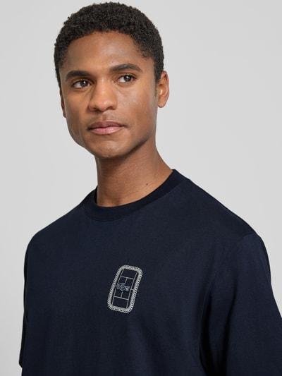Männermodel trägt dunkelblaues Regular Fit T-Shirt aus reiner Baumwolle Modell 'CN Tenniscourt Backprint' von Lacoste, Nahaufnahme Oberkörper, Herren T-Shirt.