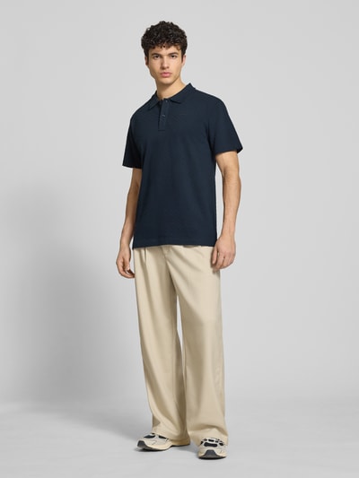 Männermodel trägt Regular Fit Poloshirt mit Logo von G-Star Raw, Reine Baumwolle, Knopfleiste, dunkle Farbe, Ganzkörperansicht von vorne. Rückenlänge bei Größe M: 74 cm.