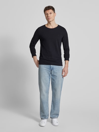 Männermodel trägt Regular Fit Langarmshirt aus reiner Baumwolle Modell 'JAAMES' von Armedangels in Schwarz, unifarben, Ganzkörperansicht von vorne.