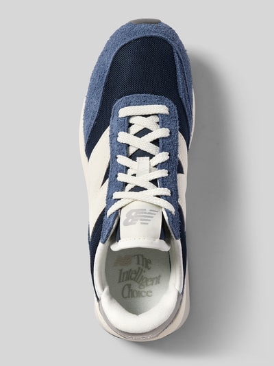 Produktfoto, Sneaker mit Label-Details Modell 'U370' von New Balance in Dunkelblau und Weiß, abgerundete Form, Schnürung, strukturierte Sohle, Absatzhöhe 5 cm, Schafthöhe 7 cm, Schaftweite 7 cm, textile und strukturierte Texturen.