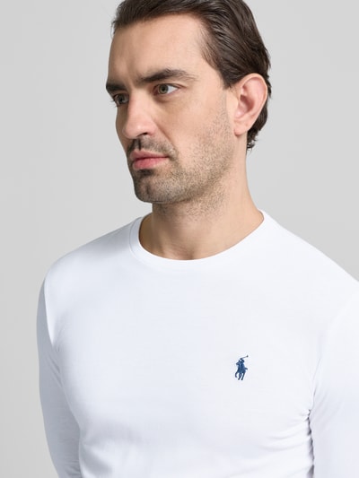Męski model nosi Custom Slim Fit Longsleeve mit Label-Stitching od Polo Ralph Lauren, biała bawełna, dekolt okrągły, krój slim fit, zbliżenie na górną część ciała.