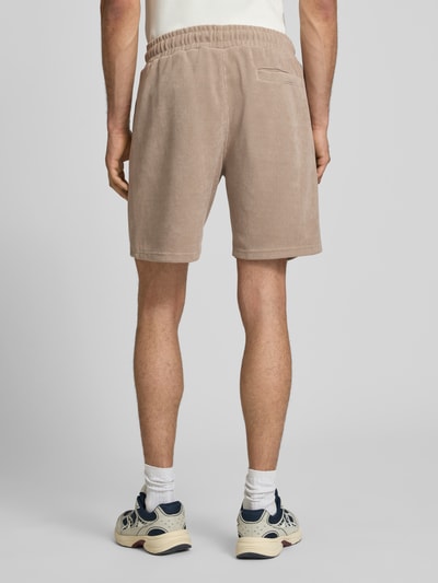 Männermodel trägt Relaxed Fit Shorts mit structuurpatroon model 'Lagos' van Pegador in beige uit elastische materiaalmix, bandwijdte maat M 38 cm, binnenbeenlengte maat M 21 cm, elastische band, heren korte broek, structuur, ganzkörperansicht achteraan.