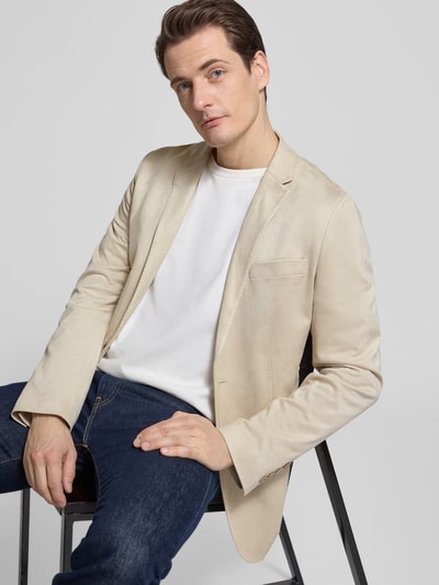 Męski model nosi Slim Fit Sakko mit Reverskragen od Antony Morato, mieszanka materiałów z dodatkiem streczu, kieszenie z patką, zapięcie na guzik, długość tyłu w rozmiarze 50: 72 cm, szerokość ramion w rozmiarze 50: 45 cm, długość rękawów w rozmiarze 50: 67 cm, jasny beż, gładka tekstura, widok całego ciała z przodu.