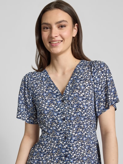 Frauenmodel trägt Minikleid aus reiner Viskose Modell 'EVIDA' von Only, blaues Allover-Muster, tailliert, V-Ausschnitt, Nahaufnahme Oberkörper.