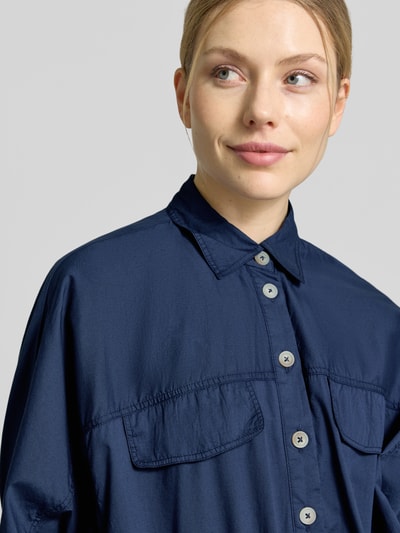 Kobiece model prezentuje Blouson aus Baumwolle mit Knopfleiste od Emily Van den Bergh, kolor granatowy, krój regular fit, wykładany kołnierz, listwa guzikowa, rękawy z zakładką, bawełna, szerokość ramion w rozmiarze 36: 45 cm, szerokość klatki piersiowej w rozmiarze 36: 52 cm, długość tyłu w rozmiarze 36: 53 cm, długość rękawów w rozmiarze 36: 20 cm, zbliżenie na górną część ciała.