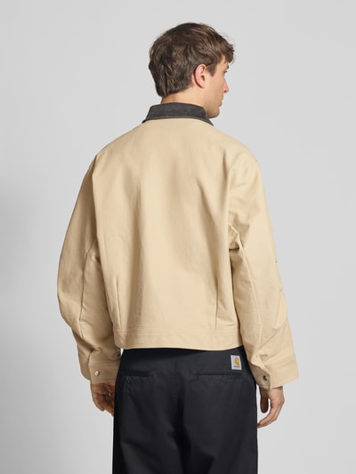 Männermodel trägt Regular Fit Jeansjacke aus reiner Baumwolle von adidas Originals in Beige mit Umlegekragen, Rückansicht Ganzkörperansicht.