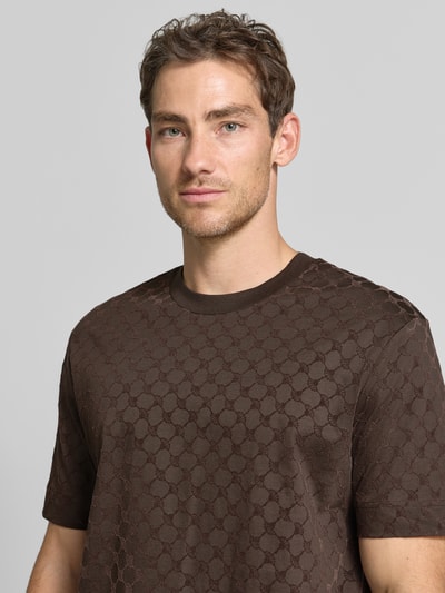 Männermodel trägt Regular Fit T-Shirt aus reiner Baumwolle Modell 'Varo' von JOOP! COLLECTION, braun gemustert, Nahaufnahme Oberkörper.