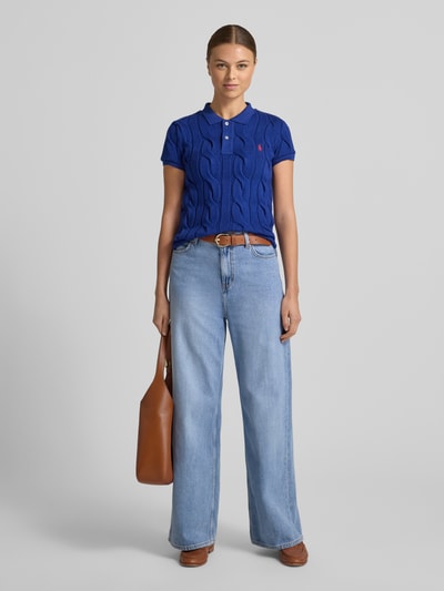 Frauenmodel trägt Koszulkę polo mit wyhaftowanym logo od Polo Ralph Lauren z bawełny, krój regular fit, kołnierzyk polo, krótka listwa guzikowa, długość tyłu 55 cm w rozmiarze S, kolor niebieski, całkowity widok z przodu.