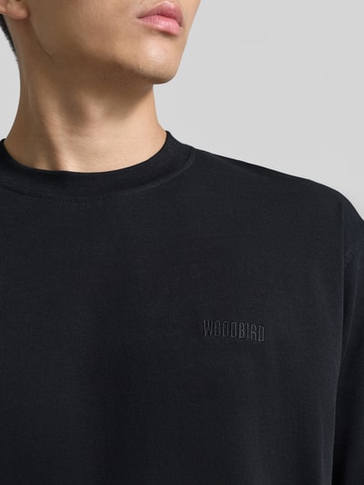 Mężczyzna nosi Regular Fit T-Shirt aus reiner Baumwolle Modell 'Baine' von WOODBIRD, czarny kolor, okrągły dekolt, label-stitching, Nahaufnahme Oberkörper.