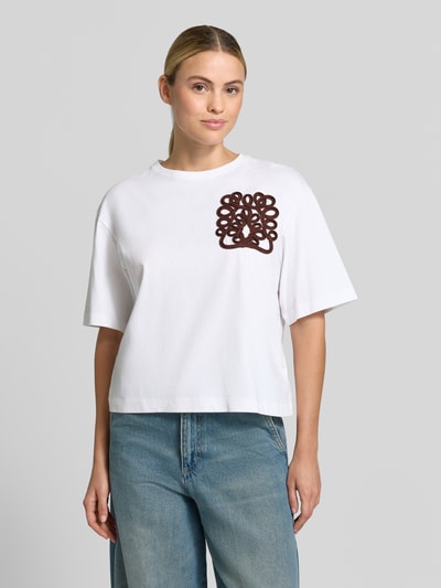 Vrouwenmodel draagt T-shirt uit katoen van Rich & Royal, los model, ronde hals, geborduurd detail, ruglengte bij maat S 54 cm, frontale lichaamsopname.