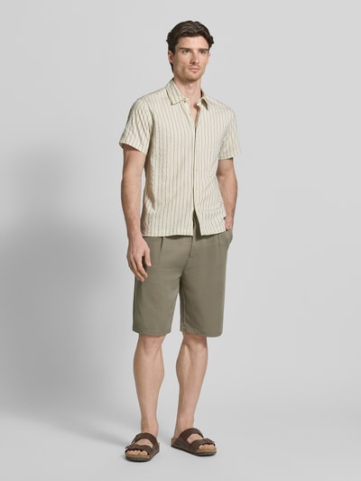 Männermodel trägt Regular Fit Freizeithemd mit Viskose-Anteil Modell 'REDFORD' von Guess, beige mit Streifen, Kentkragen, Kurzarm, Ganzkörperansicht von vorne.