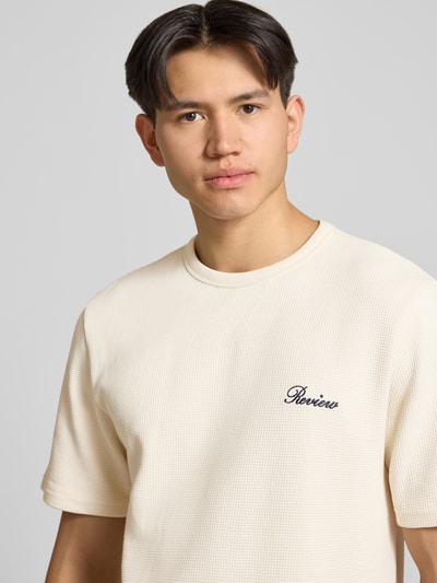 Männermodel trägt T-Shirt mit Label-Stitching von REVIEW in Beige, Baumwoll-Mix, Waffelstruktur, Gerader-Schnitt, Nahaufnahme Oberkörper.