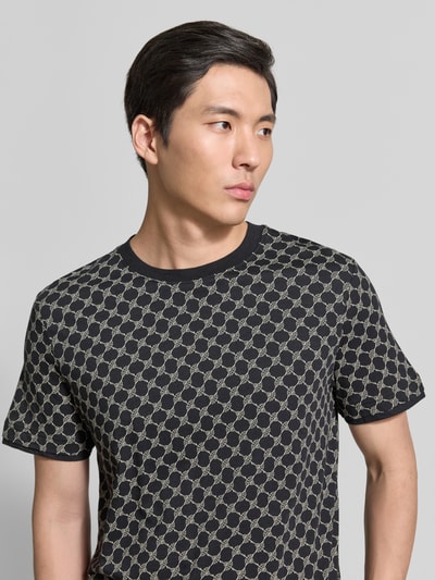 Männermodel trägt T-Shirt mit Logo-Muster und Rundhalsausschnitt von JOOP! Collection aus Baumwoll-Lyocell-Mix, Regular-Fit, Nahaufnahme Oberkörper.