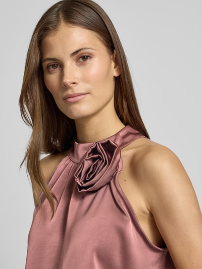 Frauenmodel trägt Blusentop aus Satin mit floraler Applikation Modell 'Rosette' von Neo Noir in Rosé mit Neckholder, Regular-Fit, Nahaufnahme Oberkörper.