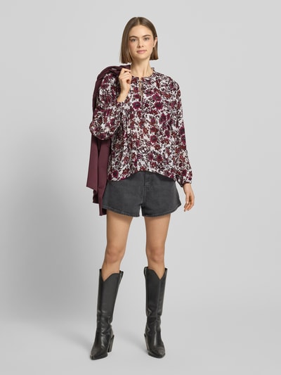 Frauenmodel trägt Oversized Langarmbluse aus reiner Viskose Modell 'LUCILA' von Pepe Jeans mit floralem Muster, Chiffon-Textur, Rüschenkragen, V-Ausschnitt, Label-Stitching-Applikation, unifarbene Optik, oversized Passform und langen Ärmeln mit Manschette; Ganzkörperansicht von vorne.