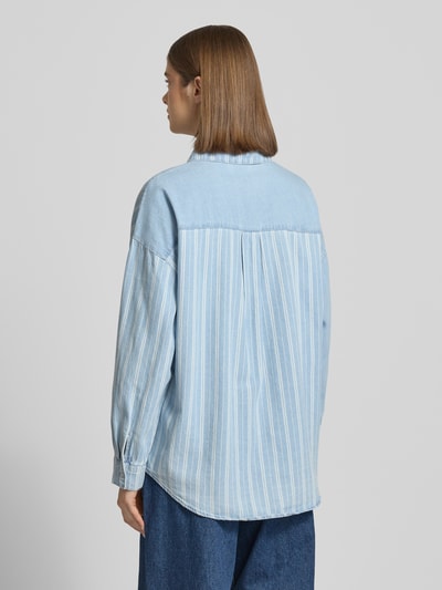 Modelka nosi Oversized Jeansbluse mit Brusttasche Modell 'KATRI' od Noisy May, jasnoniebieska bawełna, krój oversized, widok całej sylwetki z tyłu.
