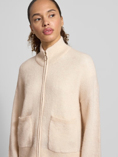 Frauenmodel trägt Regular Fit Strickjacke aus Woll-Mix Modell 'SIA' von Selected Femme in hellem Beige mit zwei Taschen, Nahaufnahme Oberkörper, Damen Strickjacke von Selected Femme.