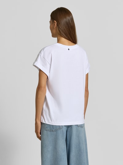 Frauenmodel trägt T-Shirt aus reiner Baumwolle von Rich & Royal, lockere Passform, weiße Farbe, glatte Textur, Ganzkörperansicht Rückansicht.
