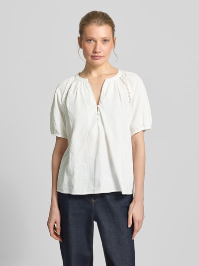 Modelka kobieca ma na sobie Loose Fit Bluse aus reiner Baumwolle Modell 'JUTTY' od Vero Moda, biała, strukturalny wzór, krótkie rękawy z elastycznym wykończeniem, haftowane detale, dekolt Henley z krótkim zapięciem na guziki, czysta bawełna, widok całej sylwetki z przodu.
