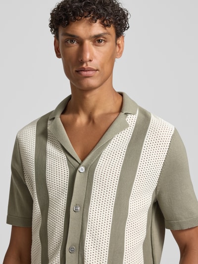 Männermodel trägt Regular Fit vrijetijdsoverhemd met kentkraag model 'Galvo' van JOOP! collectie, puur katoen, knoopsluiting, schouderbreedte 46 cm, mouwlengte 26 cm, ruglengte 68 cm, verticale strepen in olijfgroen en ecru met gehaakte textuur, nahaufnahme bovenlichaam.