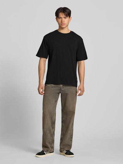 Männermodel trägt Oversized T-Shirt Modell 'FISHER' von Blend aus Reine Baumwolle, Rundhalsausschnitt, schwarze Farbe, Ganzkörperansicht von vorne.