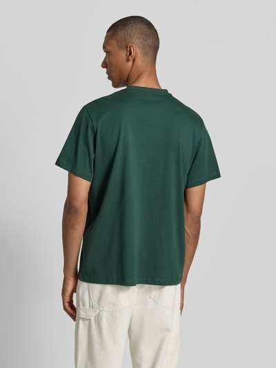 Męski model nosi zielony Relaxed Fit T-Shirt aus reiner Baumwolle Modell 'ASPEN' von SELECTED HOMME, prosta tekstura, pełny tył, Ganzkörperansicht Rückansicht