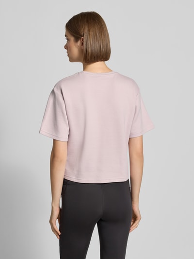 Frauenmodel trägt Relaxed Fit T-Shirt aus Häkelspitze von PUMA in zartem Rosa, glatte Textur, Damen T-Shirt, Ganzkörperansicht Rückansicht.